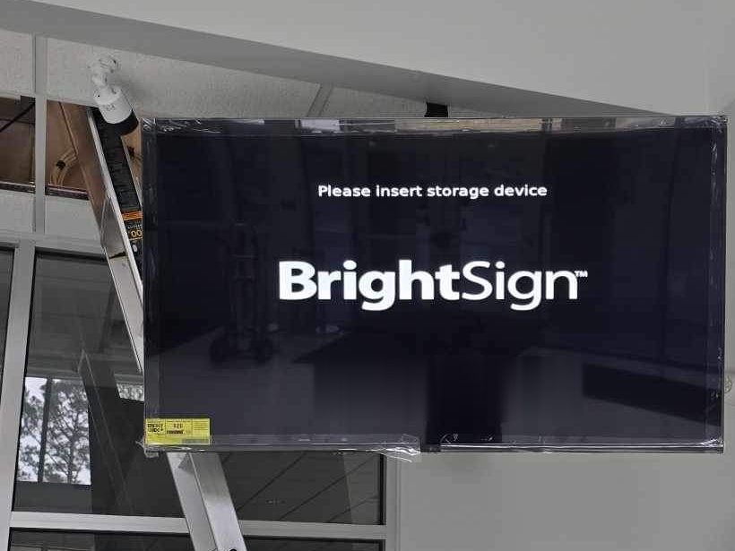 Commercial display wall-mounted in a lobby, running a BrightSign digital signage player